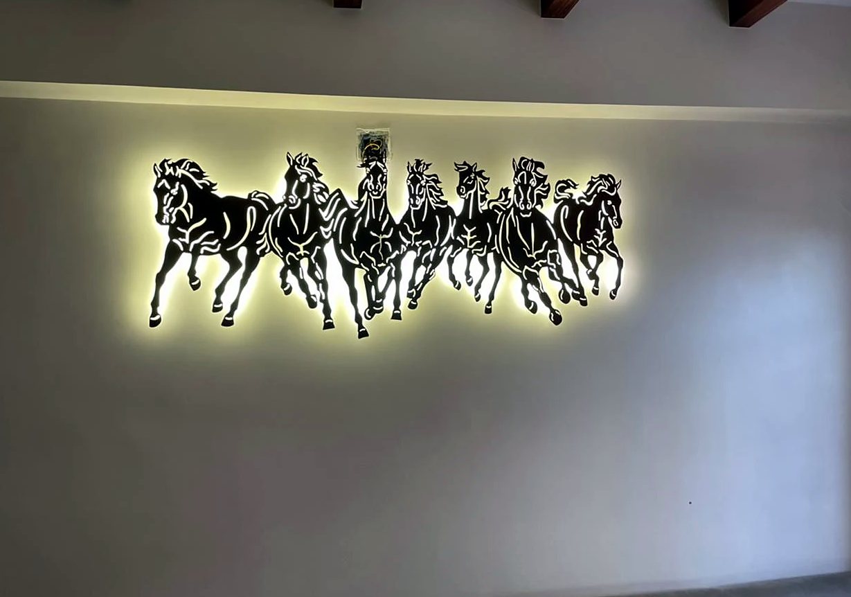 Backlit seven running horses laser-cut metal wall art on a living room wall