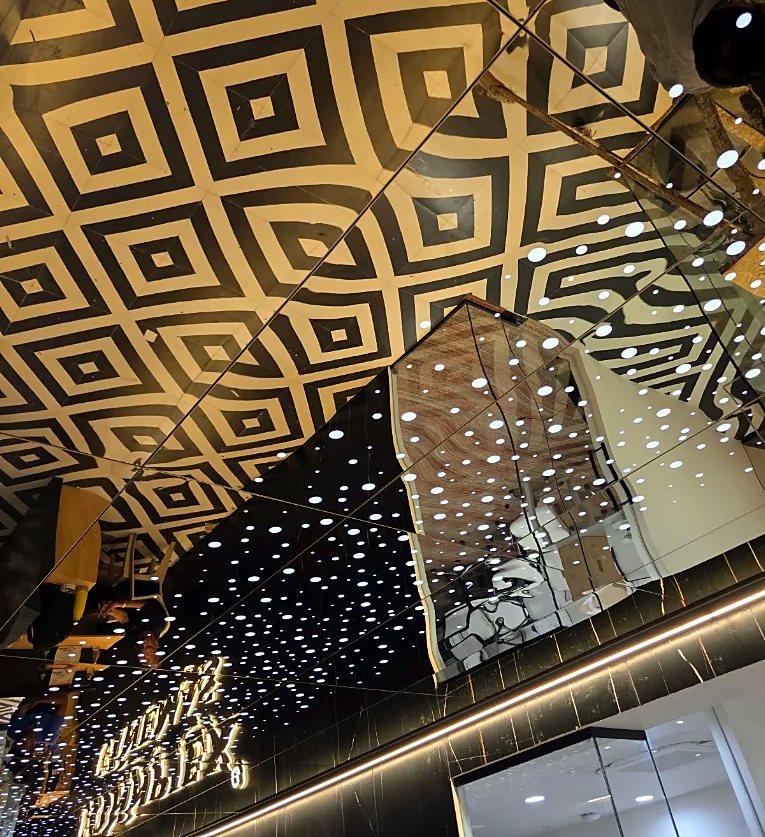 Laser-cut geometric ceiling screens in black and gold, Ahmedabad restaurant